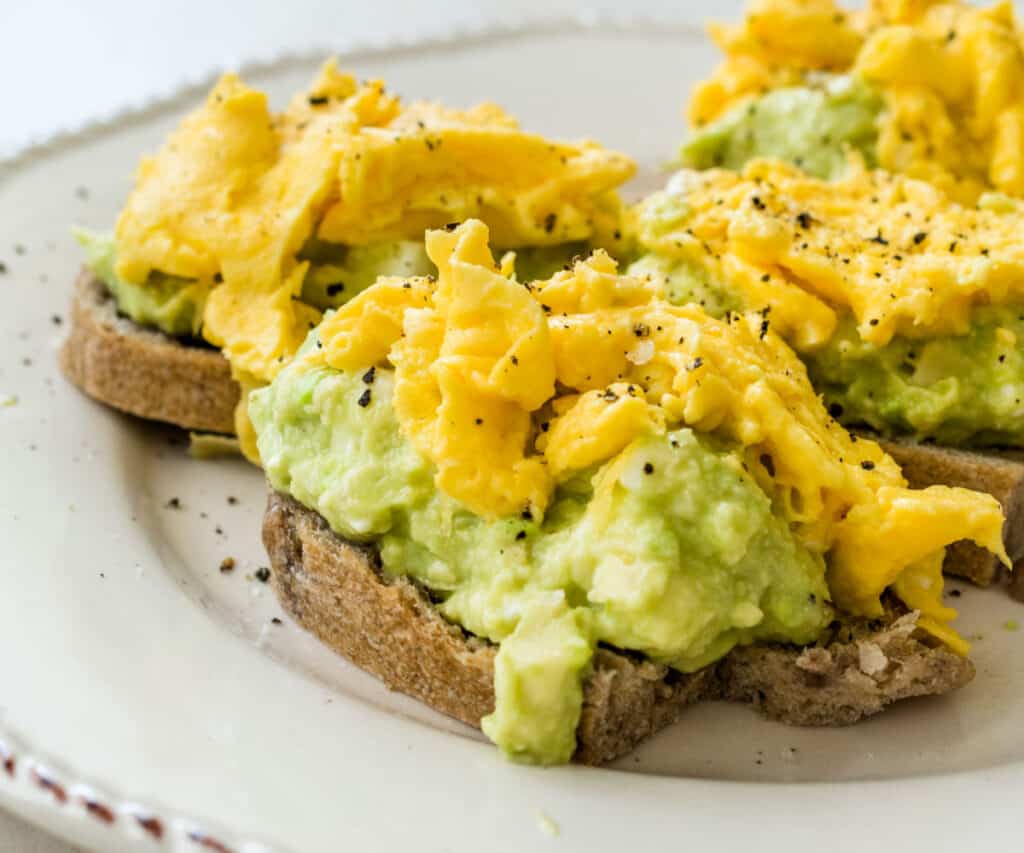 3 pieces of avocado toast covered with scrambled eggs