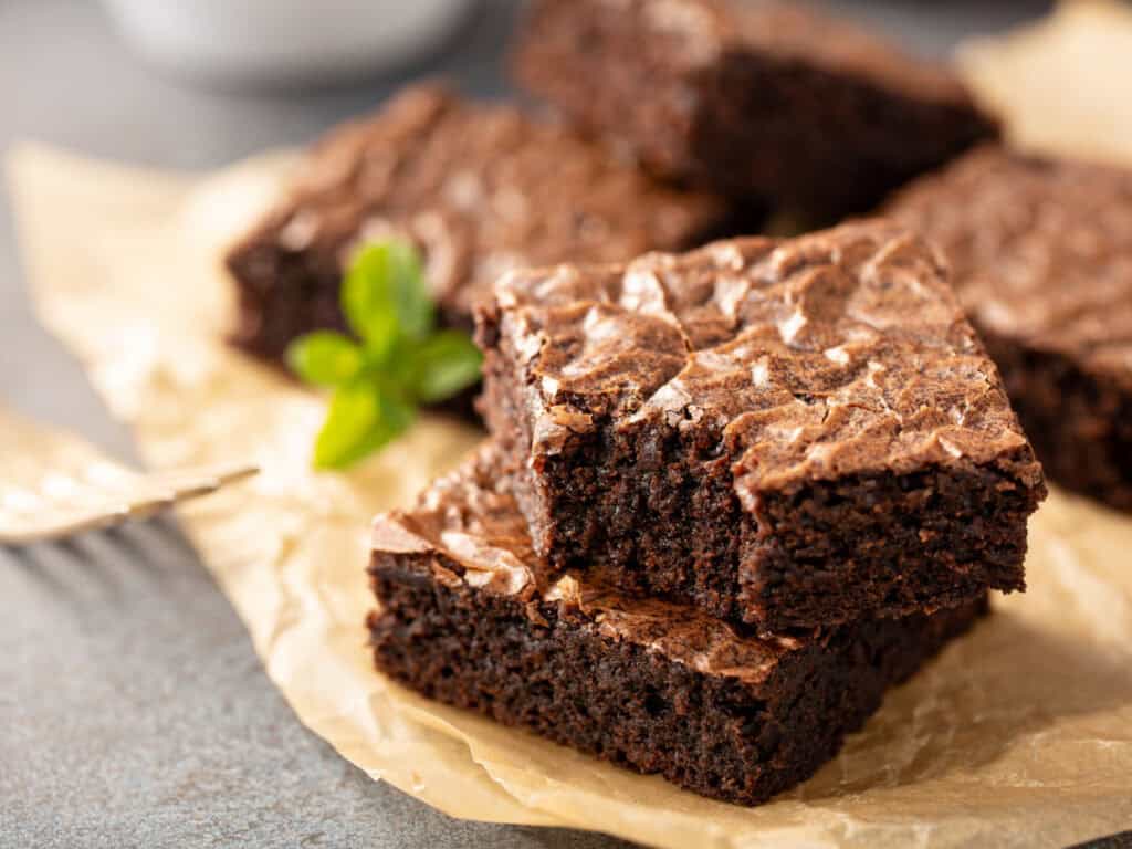 brownies on parchment with a basil leaf in the background
