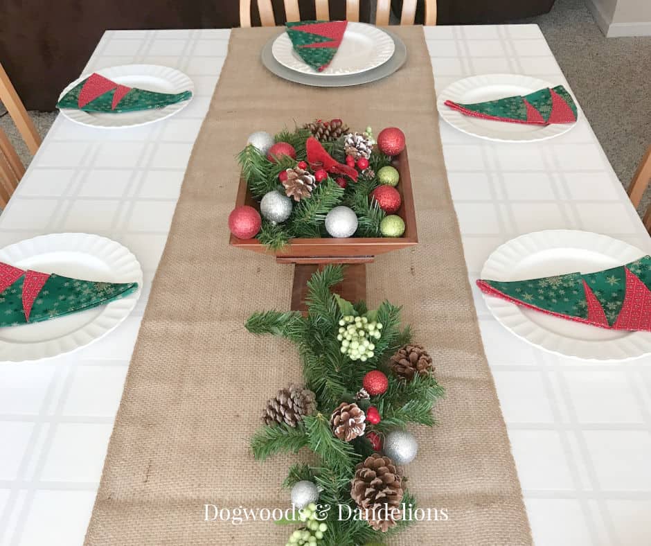 a table with a burlap runner decorated for Christmas