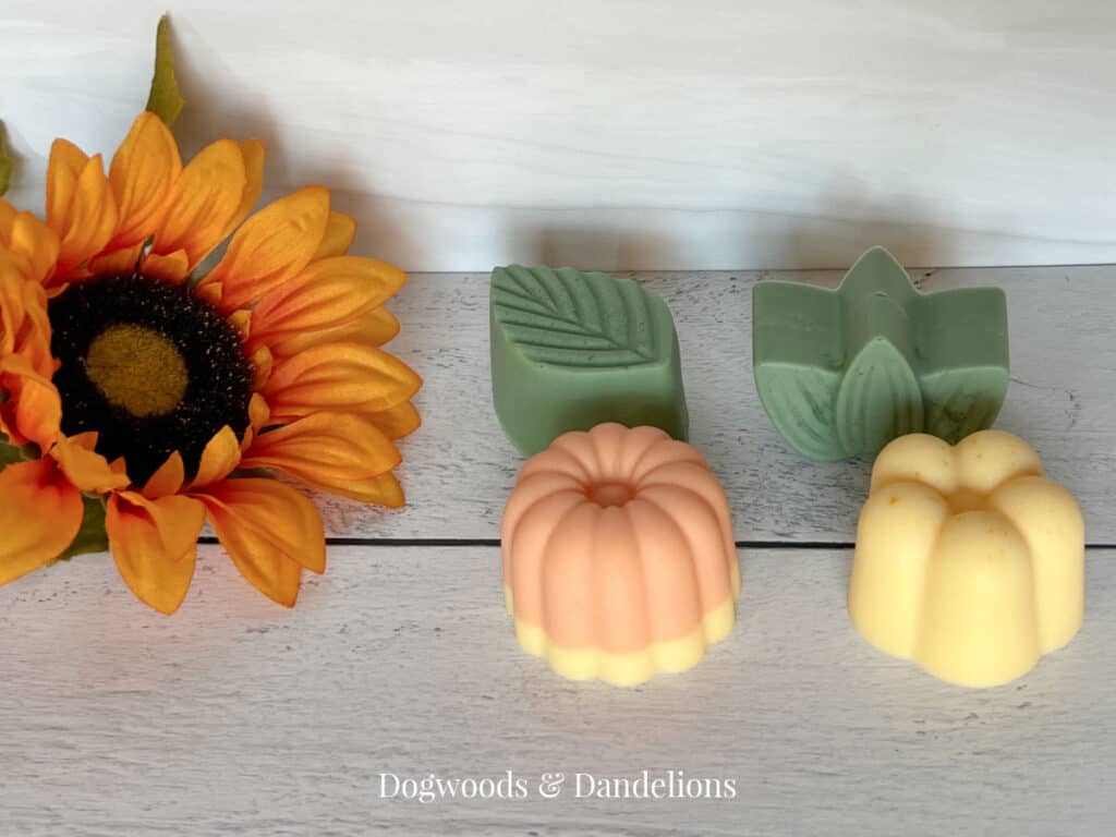 2 flower soaps and two leaf soaps beside an orange flower.