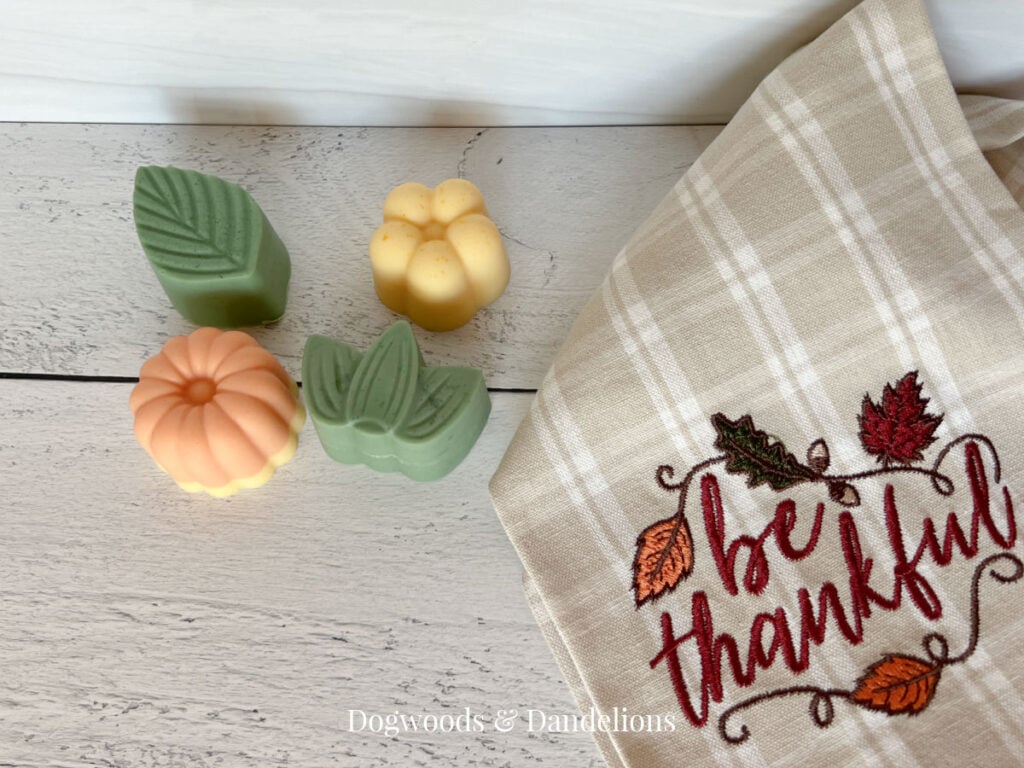 2 flower soaps and two leaf soaps beside a towel that says "be thankful".