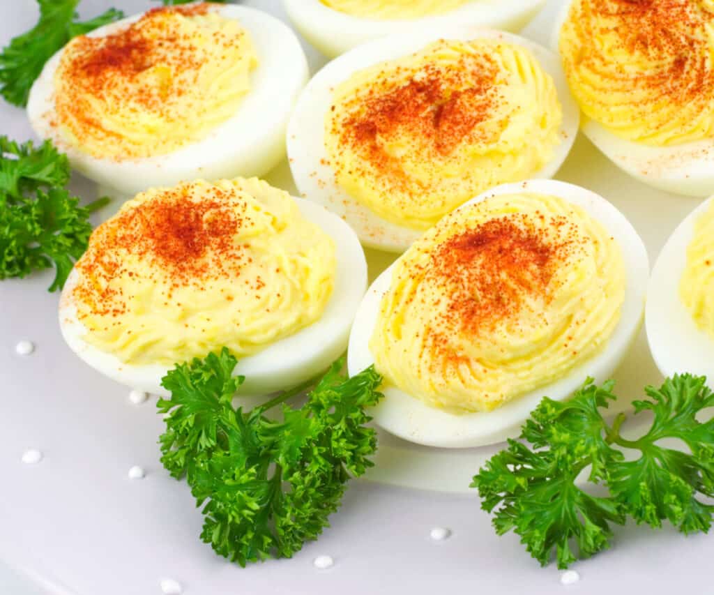 a plate of deviled eggs with parsley on the side
