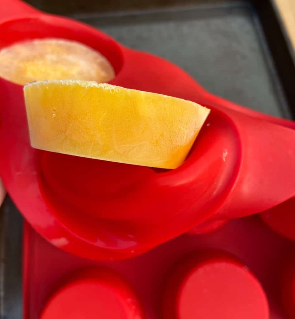 A frozen egg being removed from a silicone muffin pan.