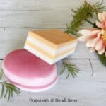 2 bars of layered soap surrounded by rosemary and a flower