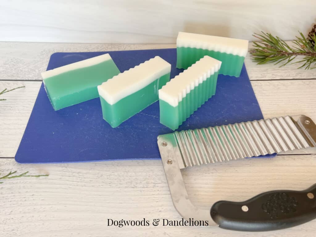 4 bars of green and white soap on a blue cutting mat beside a crinkle cutter.